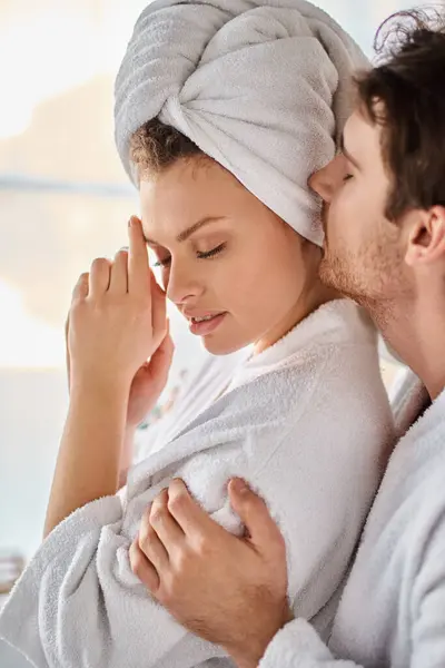 Couple in love in bathrobes, hugging each other, man kissing his girlfriend tenderly — Stock Photo