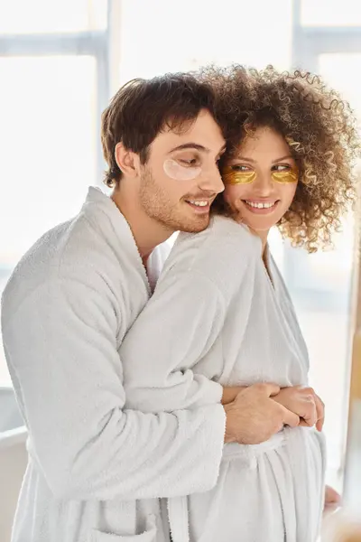 Портрет счастливой пары с повязками на глазу, обнимающей в ванной и улыбающейся вместе — стоковое фото
