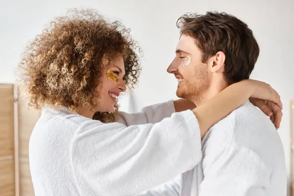 Portrait of happy couple with eye patches  hugging in bathroom and smiling, looking at each other — Stock Photo