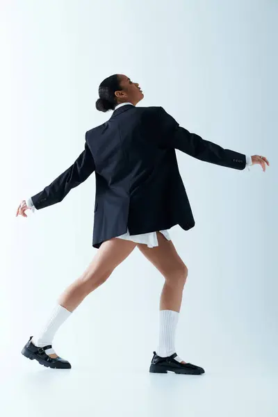 Giovane donna afroamericana indossa un abito nero e calzini bianchi, trasudando raffinatezza. — Foto stock
