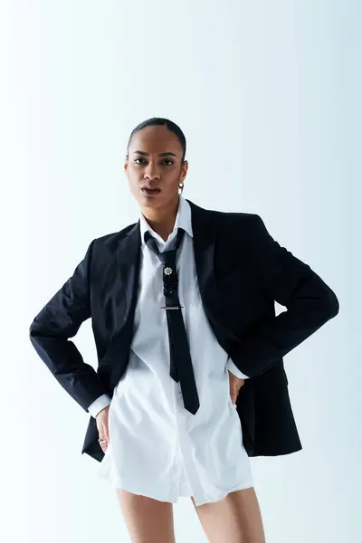 A young African American woman confidently poses in a suit and tie in a studio setting. — Stock Photo