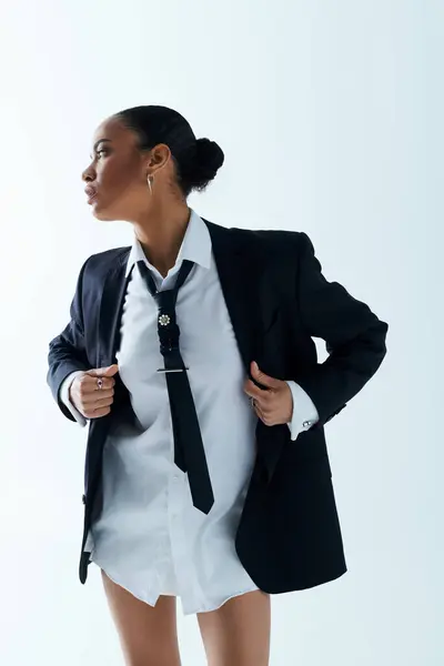 Joven mujer afroamericana con camisa blanca y corbata negra en un ambiente de estudio. - foto de stock