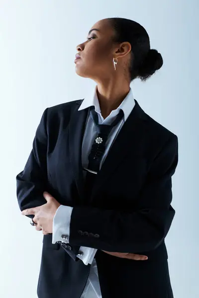 Joven mujer afroamericana de 20 años, de pie con los brazos cruzados en traje y corbata. - foto de stock