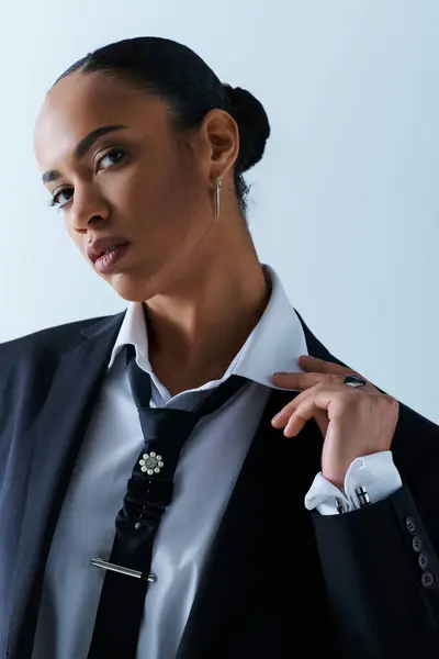 A stylish young African American woman in confidently wears a suit and tie in a studio setting. — Stock Photo