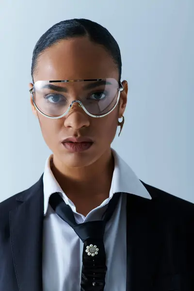 Joven mujer afroamericana de 20 años, con confianza usando traje, corbata, gafas en el estudio. - foto de stock