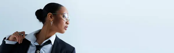 Una joven afroamericana de unos 20 años con gafas y chaqueta de traje, pancarta - foto de stock