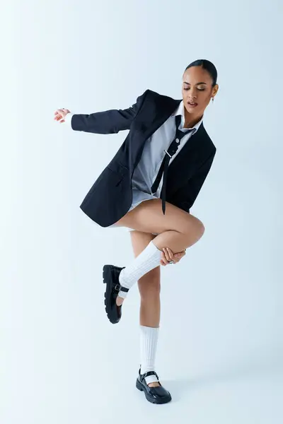 Une jeune afro-américaine d'une vingtaine d'années vêtue d'un costume et d'une cravate dansant gracieusement — Photo de stock