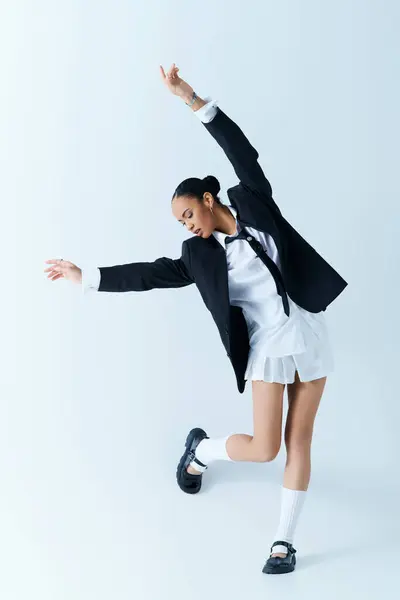 A young African American woman dressed in a suit and skirt, gracefully dancing in a studio — Stock Photo