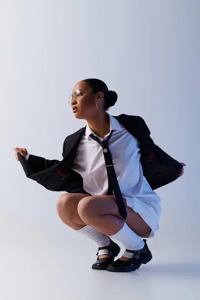 A young African American woman in a suit and tie kneeling down confidently — Stock Photo
