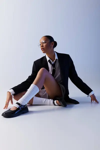 Eine elegante junge Afroamerikanerin in Anzug und Krawatte sitzt selbstbewusst auf dem Boden. — Stockfoto
