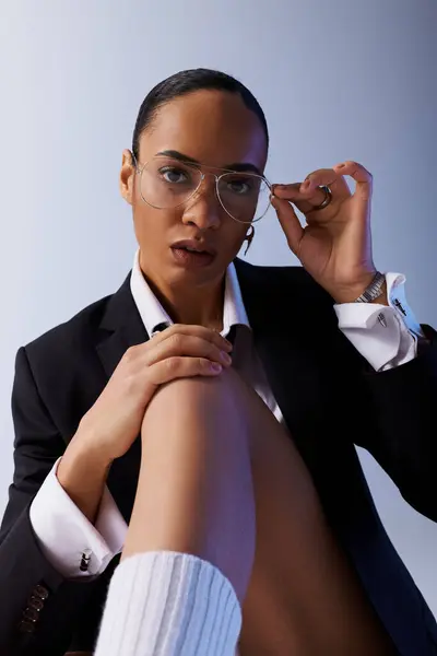 Une jeune afro-américaine dans un costume élégant et des lunettes frappe une pose pour la caméra. — Photo de stock
