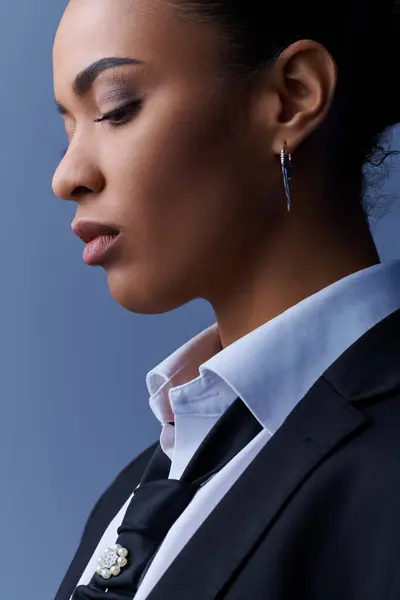 Young African American woman in suit and earrings gazes into the distance. — Stock Photo