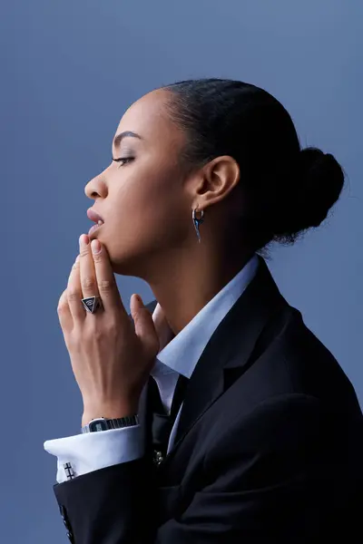 Una giovane donna afroamericana, elegantemente vestita con un abito, tiene elegantemente le mani unite in un ambiente da studio. — Foto stock