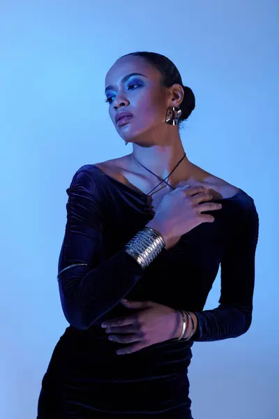 A young African American woman in a chic black dress striking a pose in a studio setting. — Stock Photo