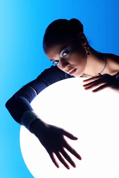 Uma jovem afro-americana coloca as mãos em uma esfera mística e brilhante. — Fotografia de Stock