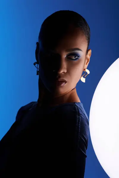 Uma jovem afro-americana cativada por uma esfera branca em um estúdio. — Fotografia de Stock