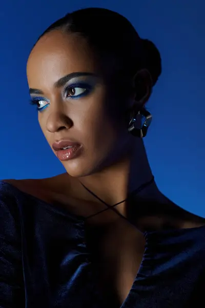 Joven mujer afroamericana en un vestido negro con bolsa, cautivadores ojos azules. - foto de stock