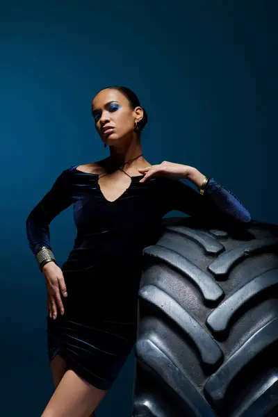 Une jeune femme afro-américaine avec une expression déterminée debout avec confiance à côté d'un pneu géant. — Photo de stock