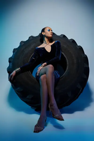 Eine junge Afroamerikanerin sitzt anmutig auf einem massiven Reifen und strahlt Vertrauen und Macht aus. — Stockfoto