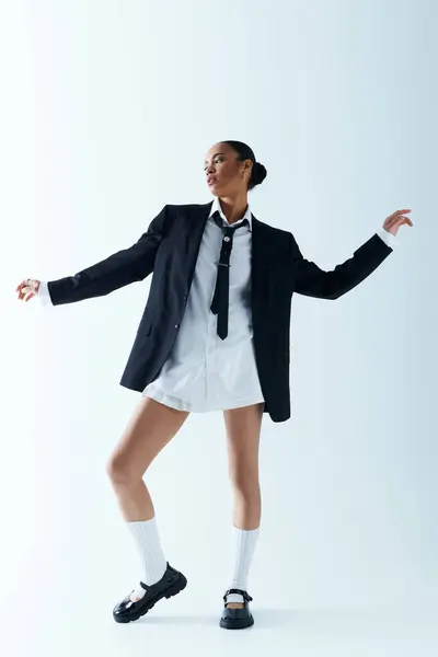 Uma jovem afro-americana de 20 anos, vestida de terno e gravata, posa confiante em um estúdio. — Fotografia de Stock