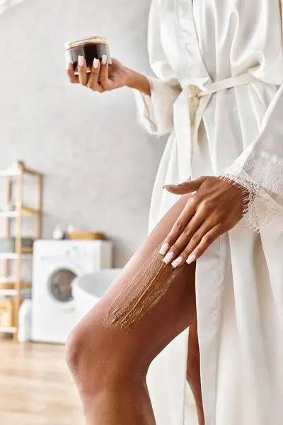 Африканська американська жінка насолоджується миттєвим розслабленням у своїй сучасній ванній кімнаті, відлущуючи тіло зі скрабом — стокове фото