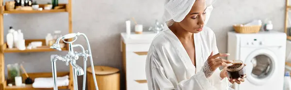 An African American woman in bathrobe exfoliating body with scrub — Stock Photo
