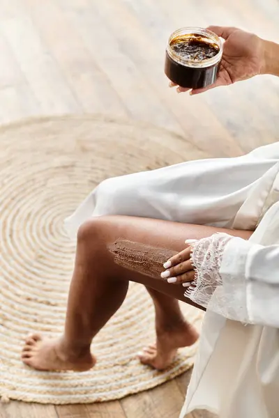 Жінка в халаті сидить на ванні, відлущуючи ногу зі скрабом — стокове фото