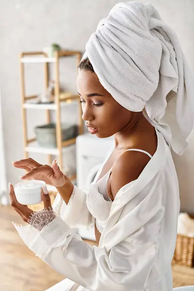 Afroamerikanische Frau mit Afro-Zöpfen hält ein Glas Creme im modernen Badezimmer und fördert Schönheit und Hygiene. — Stockfoto