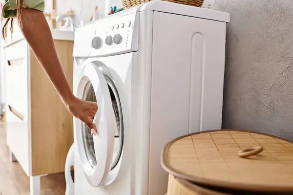 Mujer afroamericana instalando lavadora en un cuarto de lavado limpio con pisos de baldosas y paredes blancas. - foto de stock