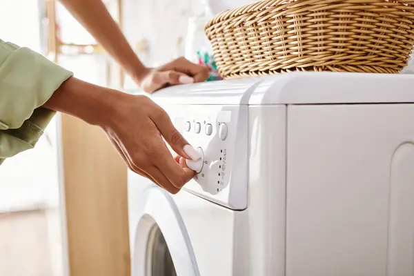 Uma mulher afro-americana carregando um secador em uma máquina de lavar roupa em um banheiro. — Fotografia de Stock