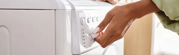 An African American woman loading a dryer onto a washing machine in a bathroom, banner — Stock Photo