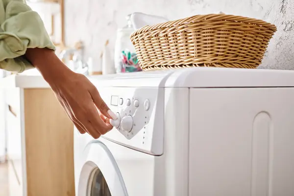 African American woman doing laundry by hand-loading clothes into a washing machine. — Stock Photo