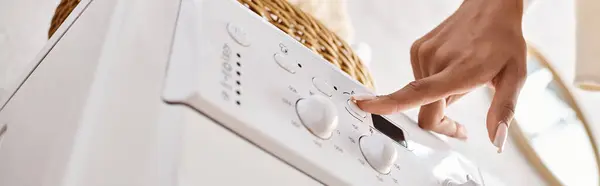 Uma mulher afro-americana pressionando botão na máquina de lavar roupa. — Fotografia de Stock