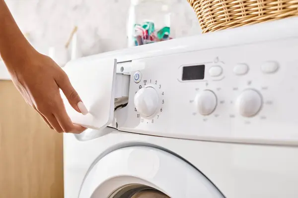 Femme afro-américaine avec des tresses afro faire la lessive dans la salle de bain, en appuyant sur le bouton sur la machine à laver. — Photo de stock