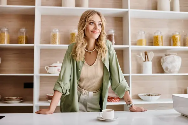 Eine Frau sitzt an einem Küchentisch mit einer Tasse Kaffee. — Stockfoto
