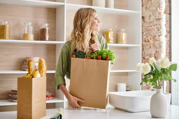 Женщина на кухне держит пакет со свежими овощами. — Stock Photo