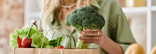 Una mujer en un apartamento sosteniendo una bolsa llena de verduras frescas. - foto de stock
