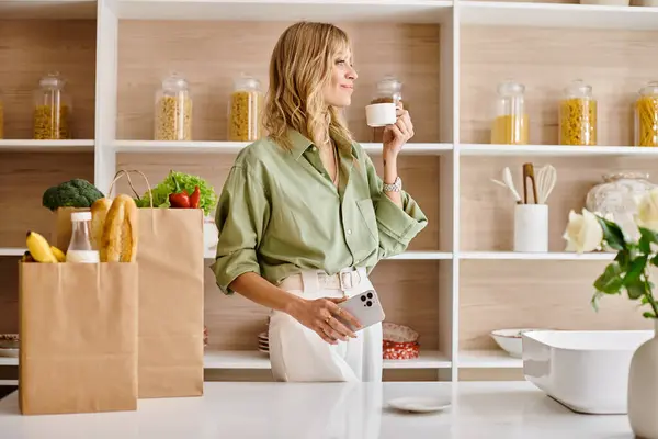 Una donna in piedi con una tazza di caffè in una cucina a casa. — Foto stock