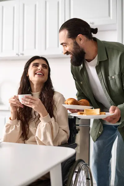 Jolly beautiful disable woman in wheelchair enjoying coffee with her husband during breakfast — Stock Photo