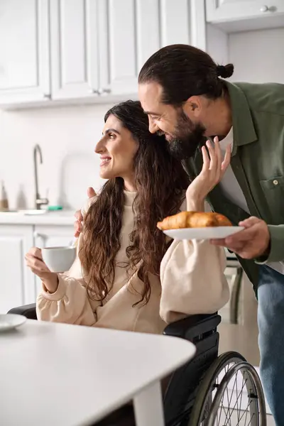 Jolly beautiful disable woman in wheelchair enjoying coffee with her husband during breakfast — Stock Photo