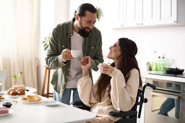 Cheerful beautiful disable woman in wheelchair enjoying coffee with her husband during breakfast — Stock Photo