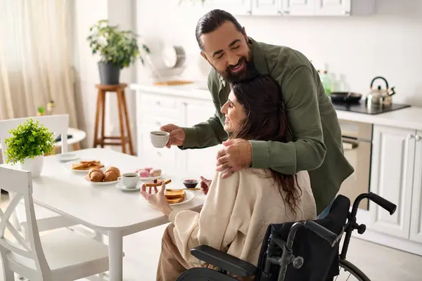 Allegra donna attraente con disabilità in sedia a rotelle fare colazione con il marito amorevole — Foto stock