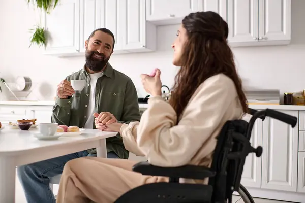 Femme joyeuse avec inclusivité dans fauteuil roulant manger des bonbons au petit déjeuner avec son beau mari — Photo de stock