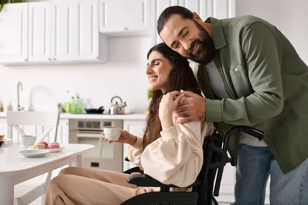 Позитивный любящий мужчина проводит время за завтраком со своей прекрасной женой-инвалидом в инвалидном кресле — стоковое фото