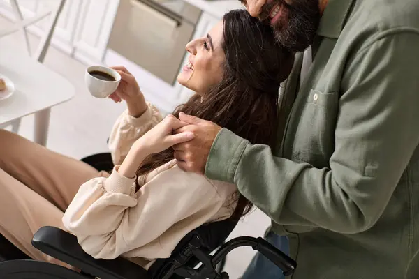 Обрезанный вид веселой женщины-инвалида в инвалидной коляске, пьющей кофе с мужем за завтраком — стоковое фото