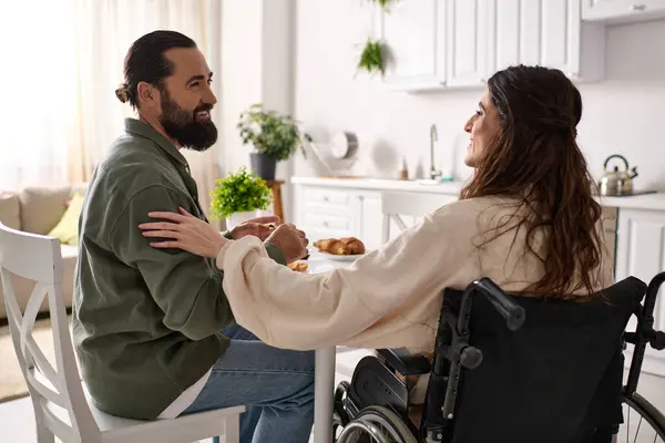 Alegre amoroso hombre pasar tiempo en el desayuno con su discapacitada hermosa esposa en silla de ruedas - foto de stock