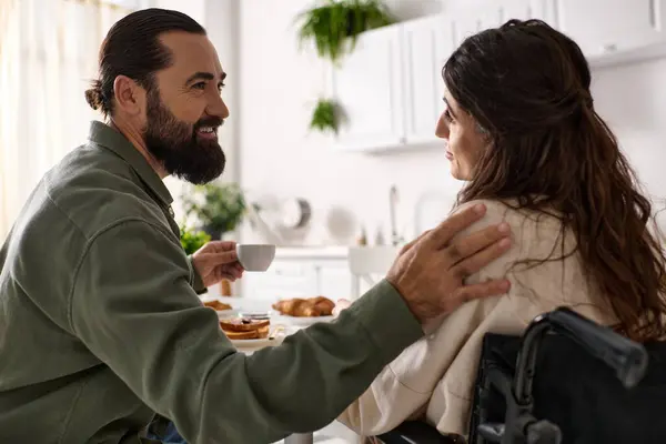 Homem alegre boa aparência desfrutando de café da manhã com sua esposa alegre deficiente em cadeira de rodas no café da manhã — Fotografia de Stock