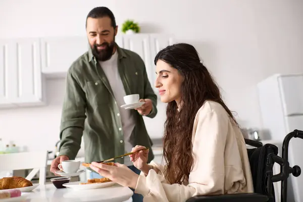 Cheerful beautiful woman with disability in wheelchair enjoying breakfast with her bearded husband — Stock Photo