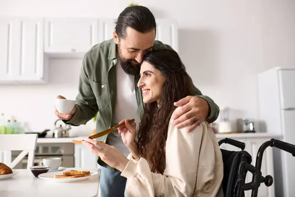 Cheerful pretty woman with disability in wheelchair enjoying breakfast with her bearded husband — Stock Photo