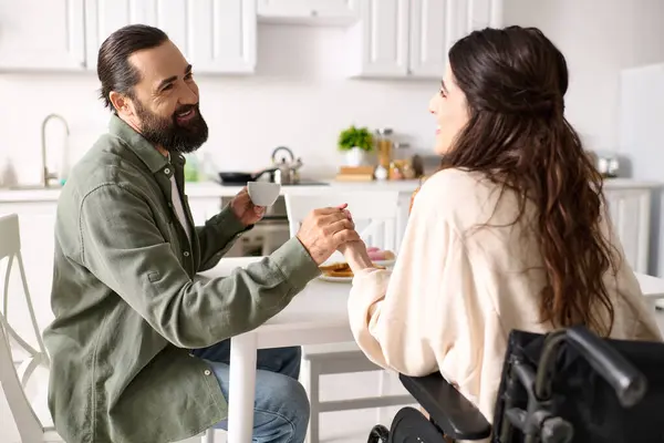 Attraktive, fröhliche Frau mit Behinderung im Rollstuhl beim Frühstück mit ihrem bärtigen Mann — Stockfoto